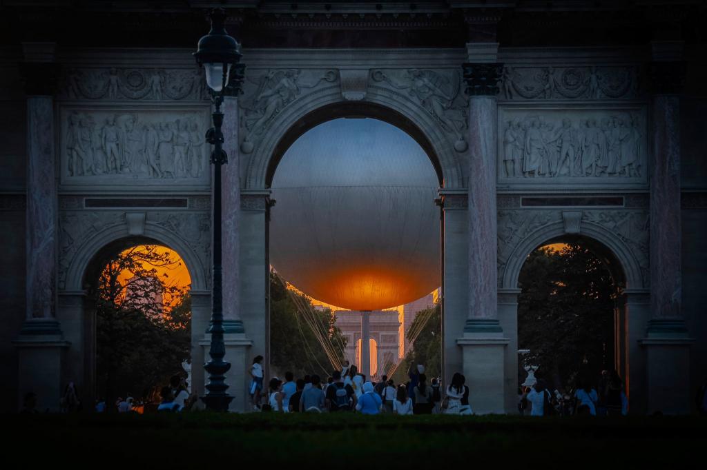 Der Heliumballon, der während der Olympischen Spiele 2024 verwendet wurde, und der Arc de Triumph sind bei Sonnenuntergang in Paris sehen. - Foto: Aurelien Morissard/AP/dpa