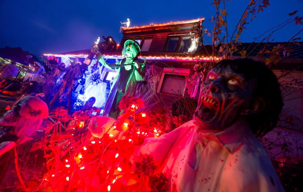 Gruselige Figuren stehen in Mettmann vor einem beleuchteten Halloween-Haus. - Foto: Henning Kaiser/dpa
