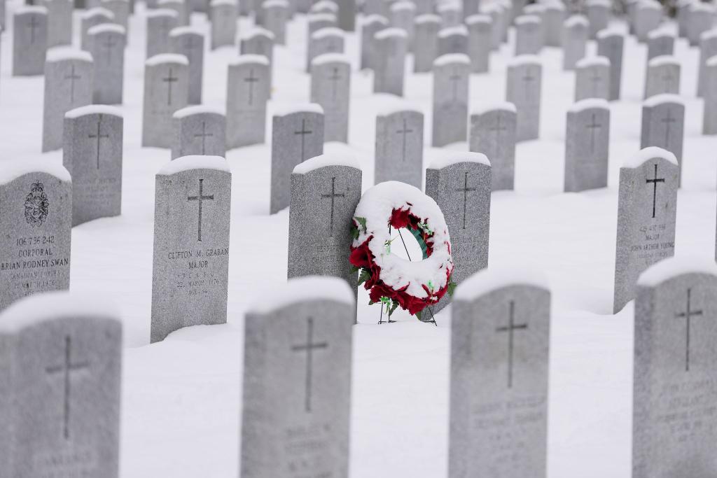 Ein schneebedeckter Kranz lehnt an einem Grabstein vor der Gedenkfeier zum Remembrance Day auf dem nationalen Soldatenfriedhof in Beachwood in Ottawa in Kanada. - Foto: Justin Tang/The Canadian Press/AP/dpa