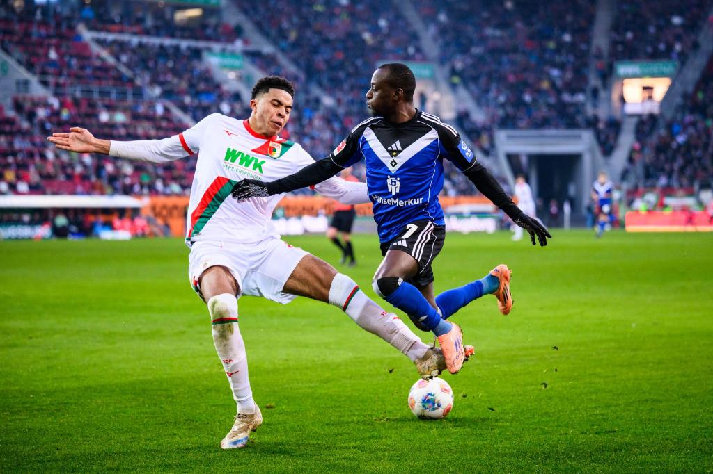 Augsburgs Noahkai Banks im Zweikampf mit Jean-Luc Dompé vom HSV. - Foto: Tom Weller/dpa