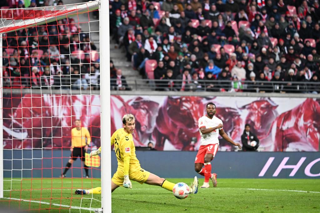 Bremens Torwart Mio Backhaus (l, Werder Bremen) und Ridle Baku (RB Leipzig) schauen dem Ball hinterher. Backhaus verhinderte mit seinen Paraden einen frühen Rückstand der Gäste in Leipzig. - Foto: Jennifer Brückner/dpa