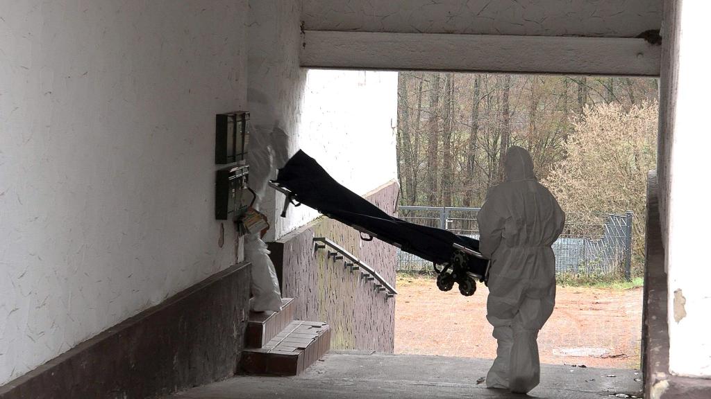Beamte der Spurensicherung bringen eine Trage in ein Wohnhaus. - Foto: Thorsten Kremers/dpa