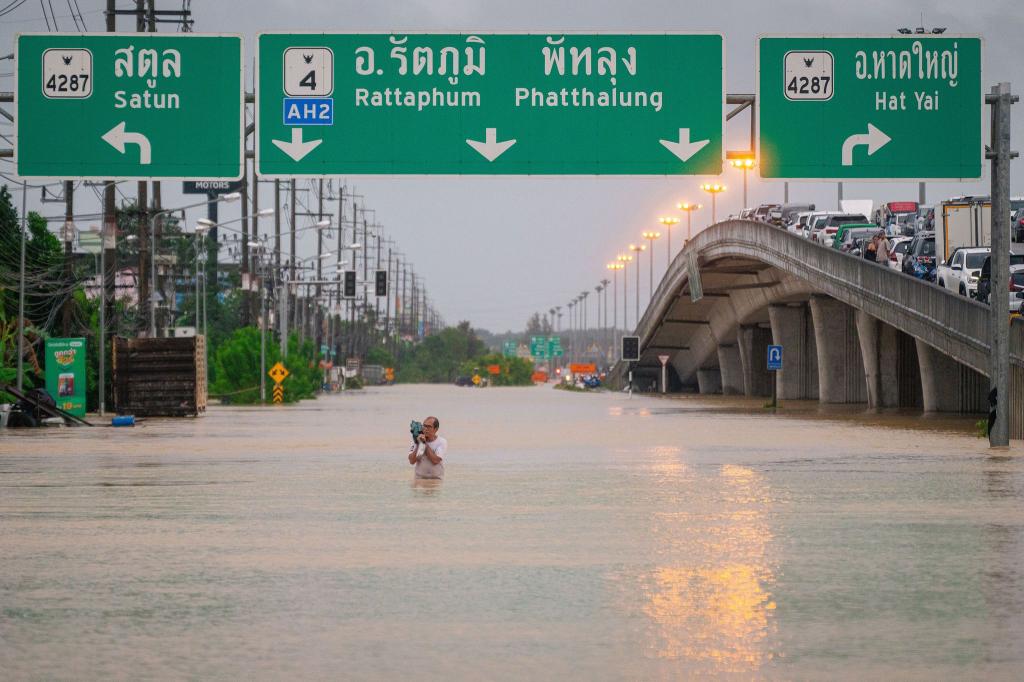 Ein Mann watet durch die Fluten in einem Vorort von Hat Yai in Thailand. - Foto: -/XinHua/dpa