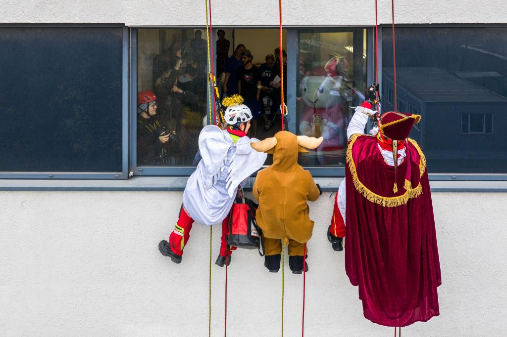 Verkleidete Höhenretter seilen sich von einem Gebäude des Herzzentrums Duisburg ab, um kleinen Patienten im Kinderherzzentrum Geschenke zu bringen. - Foto: Christoph Reichwein/dpa
