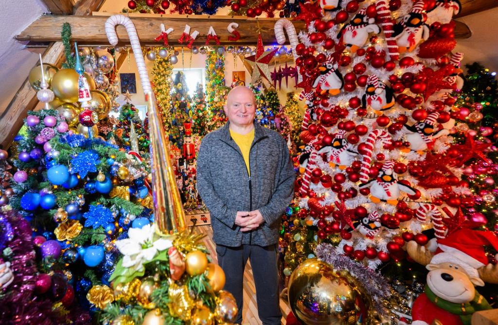Thomas Jeromin steht inmitten von Weihnachtsbäumen in seinem Haus im Landkreis Schaumburg. - Foto: Julian Stratenschulte/dpa
