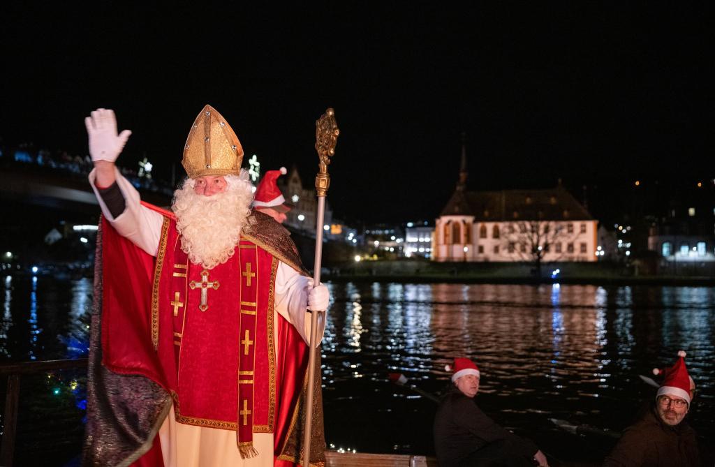 Von zahlreichen Fackelschwimmern begleitet ist der Nikolaus in Bernkastel-Kues in einem Ruderboot über die Mosel gekommen. - Foto: Harald Tittel/dpa
