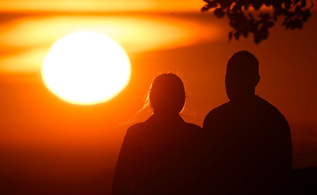 Ein Paar bei Sonnenaufgang - Foto: Julian Stratenschulte/dpa