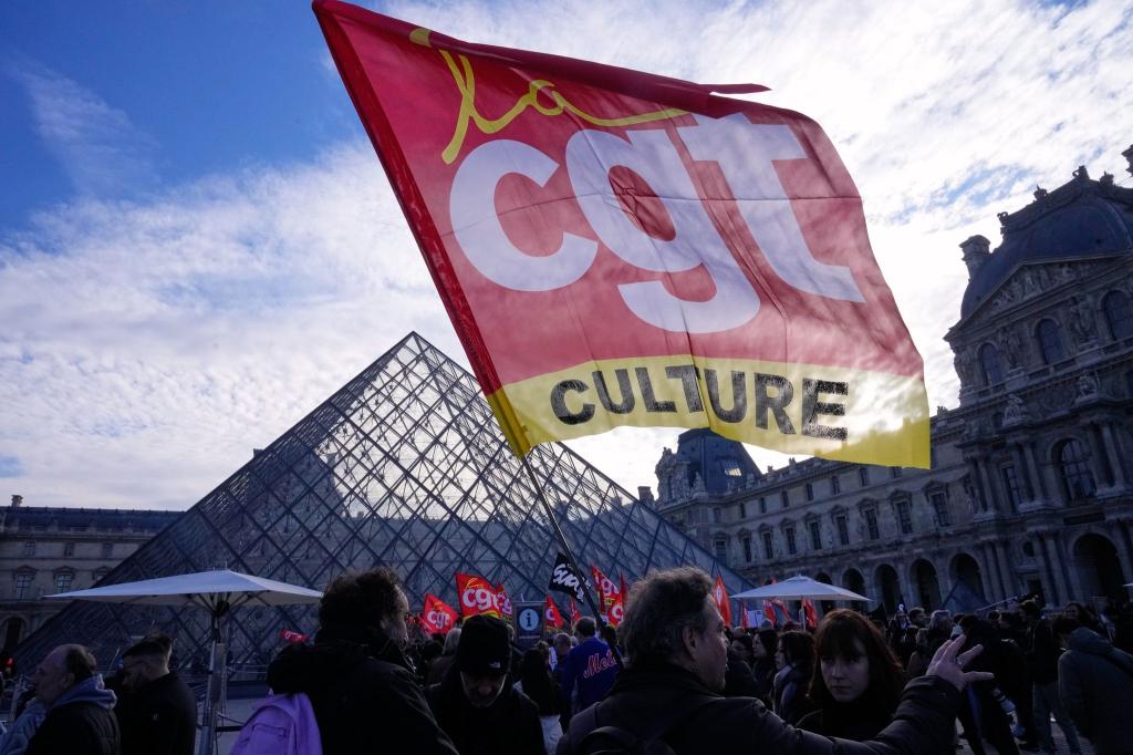 Angestellte zeigen eine Flagge der Gewerkschaft CGT vor dem Louvre, nachdem sie für einen Streik gestimmt haben. - Foto: Michel Euler/AP/dpa