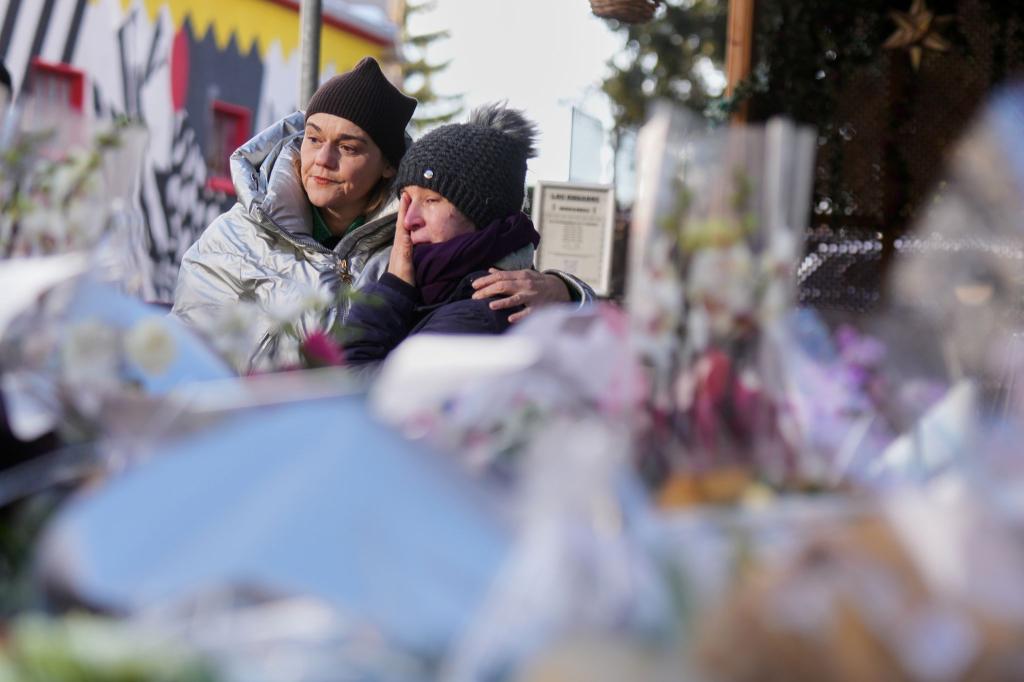 Menschen trauern hinter Blumen und Briefen in der Nähe der abgeriegelten Le Constellation Bar, wo ein verheerender Brand während der Neujahrsfeierlichkeiten Tote und Verletzte forderte. - Foto: Antonio Calanni/AP/dpa