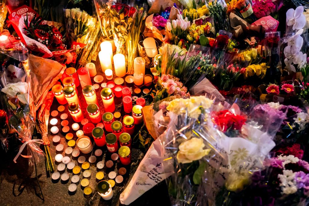 Ein Blumen- und Kerzenmeer erinnert an Tote und Verletzte in der Nähe des Brandortes. - Foto: Jean-Christophe Bott/KEYSTONE/dpa