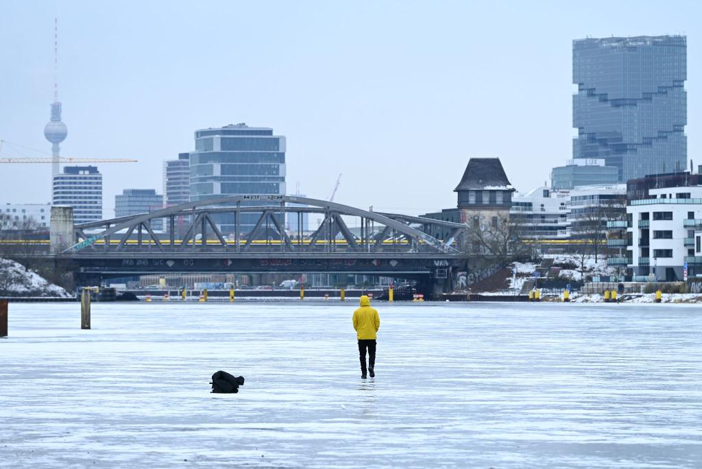 Ein Mann steht am Treptower Park in Berlin auf der zugefrorenen Spree. - Foto: Elisa Schu/dpa