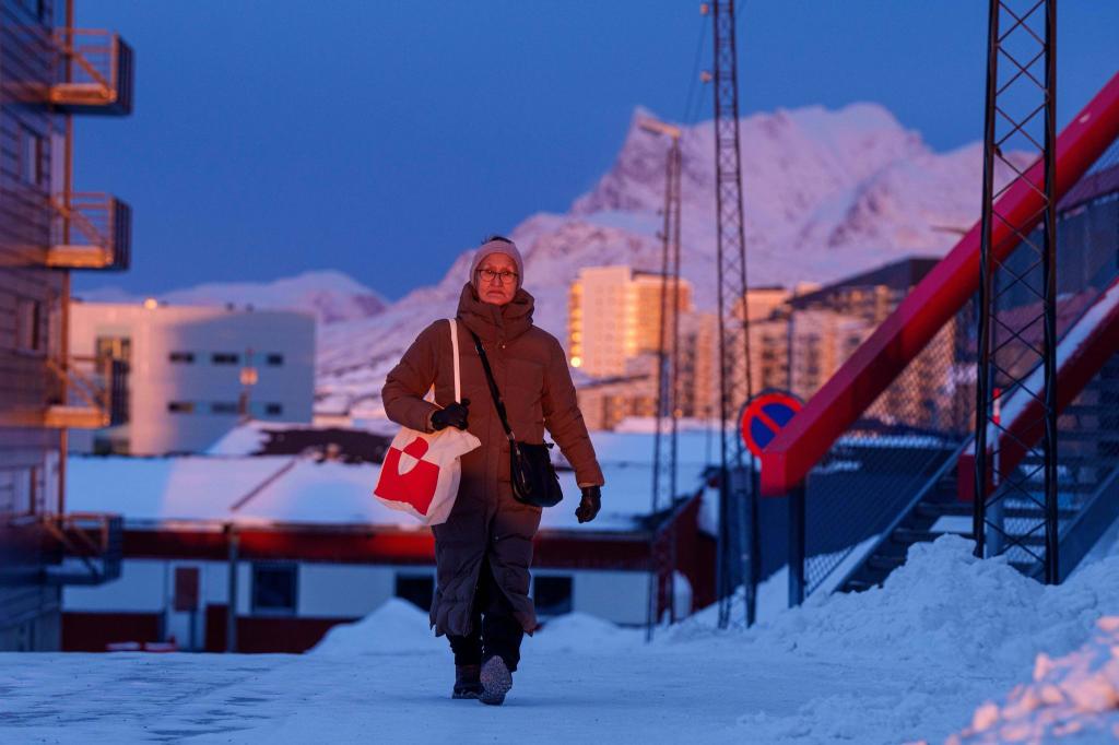 Eine Frau geht bei Sonnenuntergang auf einer Straße in Nuuk. - Foto: Evgeniy Maloletka/AP/dpa