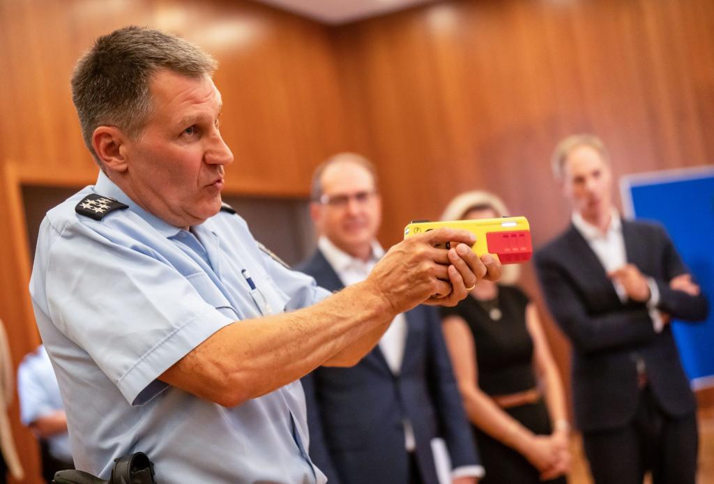 Ein Polizist erklärte die Funktionsweise eines Distanz-Elektroimpulsgeräts im vergangenen Jahr im Innnenministerium. (Archivfoto) - Foto: Michael Kappeler/dpa