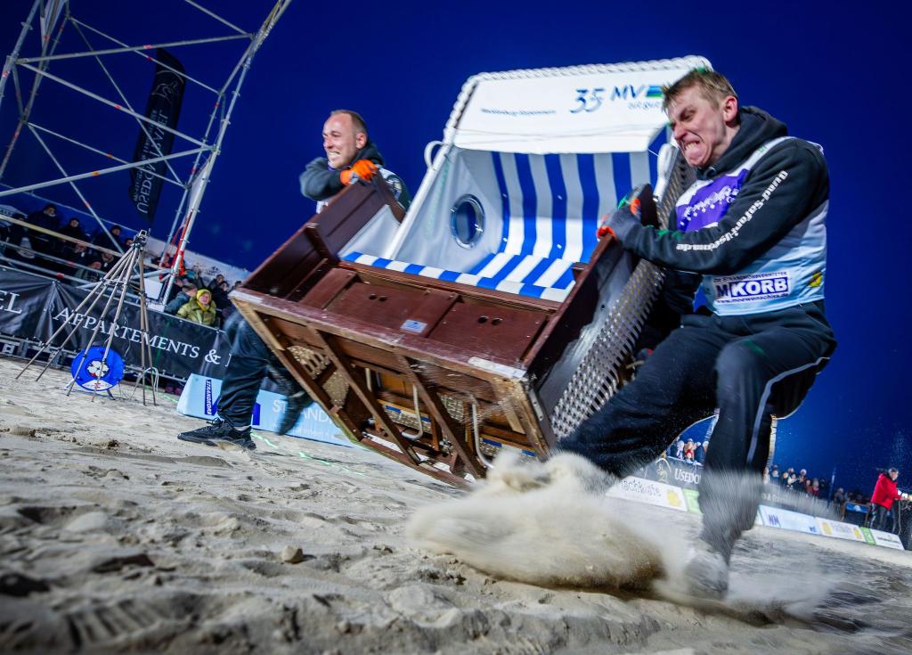 Sie geben alles: Das Team „Quad Safari Usedom“ mit Phillip Schmidt (l) und Finley Liemen (r) gewinnt den Finallauf bei der 18. Strandkorb Weltmeisterschaft auf der Insel Usedom mit einer neuen Weltrekordzeit von 4,56 Sekunden. Die Zweierteams müssen bei dem Wettkampf einen etwa 60 Kilogramm schweren Strandkorb über die 20 Meter lange Strecke über den Ostseestrand ins Ziel schleppen. - Foto: Jens Büttner/dpa