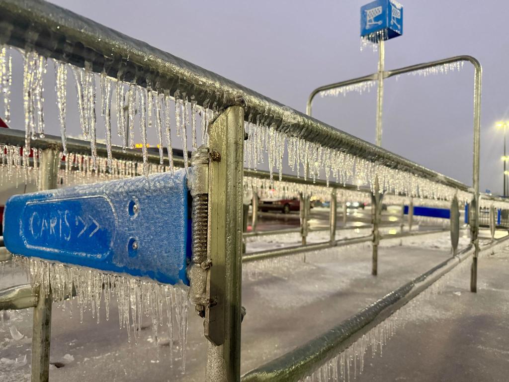 Eiszapfen hängen an einem Geländer während eines Wintersturms auf einem Parkplatz. - Foto: John Raby/AP/dpa
