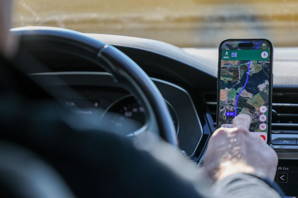 So ist es derzeit erlaubt: Das Handy steckt in der Halterung und wird nur kurz vom Fahrer beachtet. (Symbolbild) - Foto: Jan Woitas/dpa