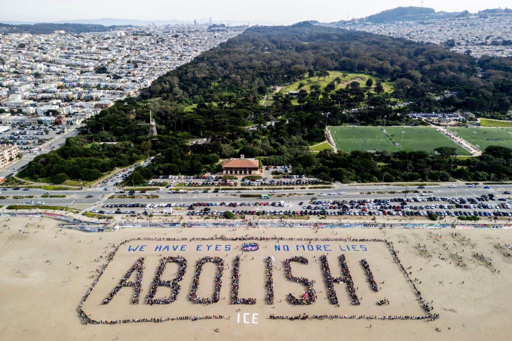 Demonstranten bilden ein menschliches Banner «We have eyes - no more lies - Abolish» am Ocean Beach in San Francisco während eines Protests gegen die US-Einwanderungsbehörde ICE. - Foto: Stephen Lam/San Francisco Chronicle via AP/dpa